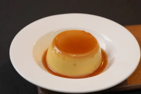 A caramel custard dessert on a white plate, shot for a restaurant menu